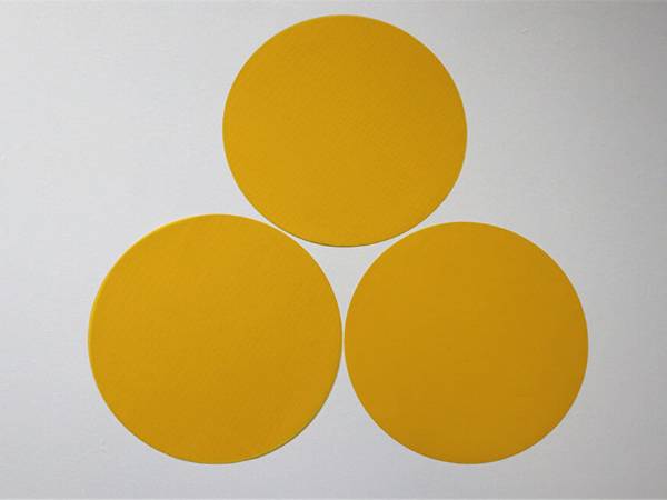 Three pieces of yellow color polyester filter disc on gray background.